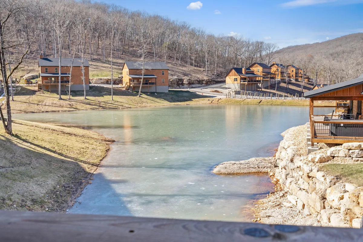 This image captures a serene view of Table Rock Lake, with wooden cabins nestled among surrounding trees. The tranquil water and natural landscape provide a clear sense of proximity to outdoor adventure and relaxation options such as boating, fishing, and family gatherings by the lake.