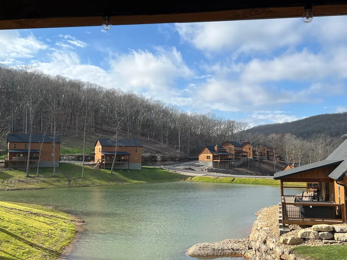 A peaceful scene showing Table Rock Lake framed by cabins, trees, and gentle hills, with soft light reflecting off the water—evoking the natural serenity and wildlife of the area.