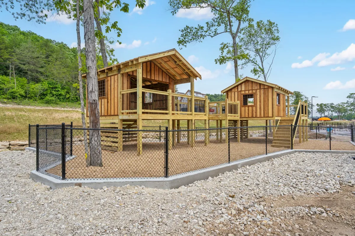 A colorful playground sits within a fenced area surrounded by trees, while children and families gather for playtime and celebration. The atmosphere is lively, safe, and oriented towards young adventurers exploring and socializing within the resort grounds.